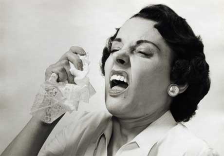 B&W photo of a woman from the 1950s sneezing