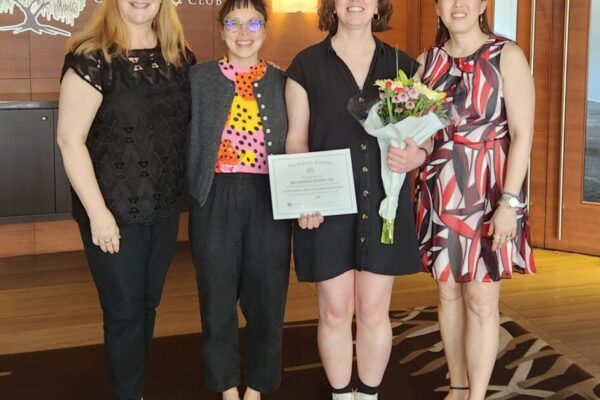 Jade & Christina are standing in the lobby of the Richmond Tennis Club, holding flowers and a certificate. Suzanne Williams on the left, Dr Sonia Tan on the right.