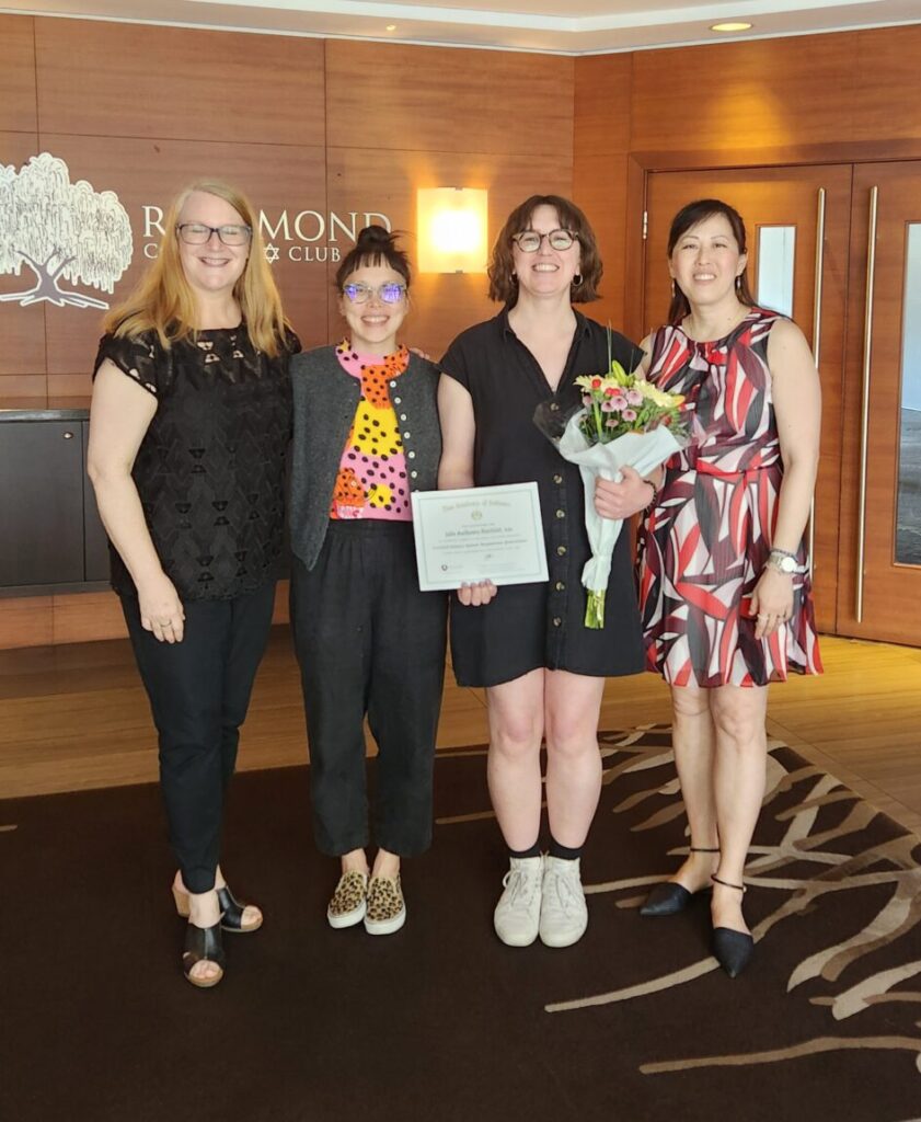 Jade & Christina are standing in the lobby of the Richmond Tennis Club, holding flowers and a certificate. Suzanne Williams on the left, Dr Sonia Tan on the right.